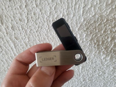 Ledger Nano S Plus hardware wallet held in hand showing compact size and metal swivel cover